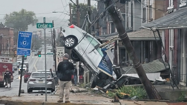 Vehicle collides with house, ends up balanced on cables